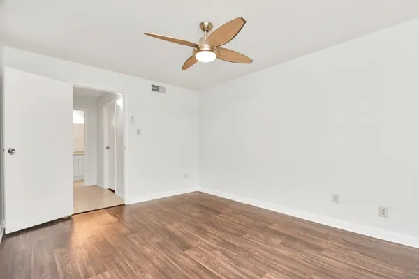 an empty room with wooden floor and a ceiling fan