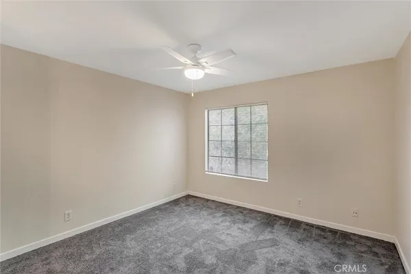 an empty room with chandelier fan and windows