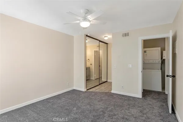 an empty room with closet and a ceiling fan