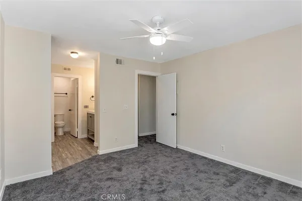an empty room with closet and a ceiling fan