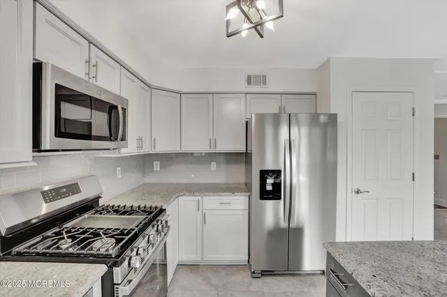 a kitchen with stainless steel appliances granite countertop a refrigerator a stove and a microwave