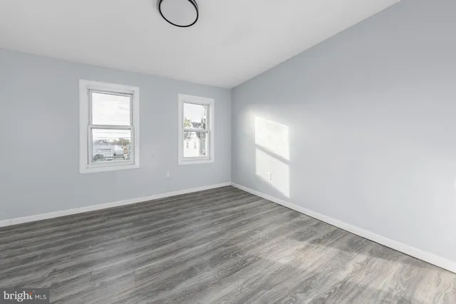 a view of an empty room with wooden floor and window