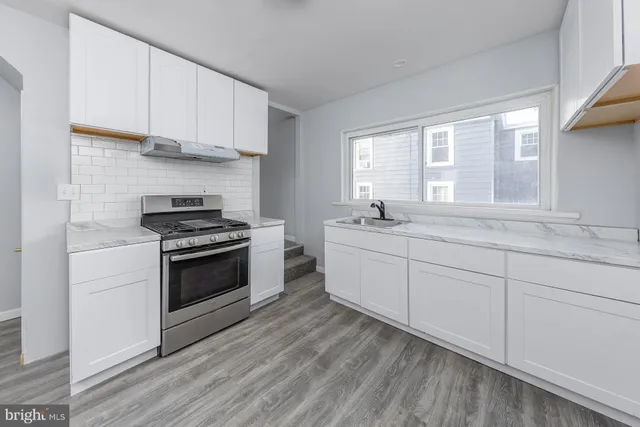 a kitchen with stainless steel appliances a white stove top oven sink and window