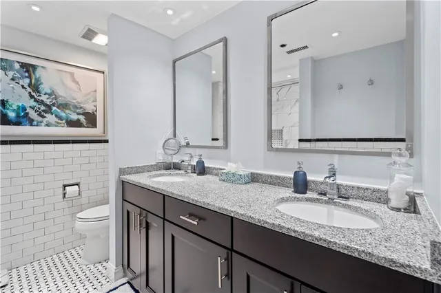 a bathroom with a granite countertop sink a toilet and a large mirror