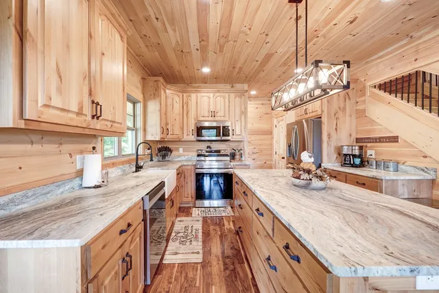 a kitchen with stainless steel appliances granite countertop a sink a stove and a wooden cabinets
