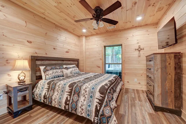 a bedroom with a large bed a flat tv screen and dresser