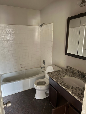874 770 South Tooele, UT 84074 - Photo 9 of 19 Bathroom featuring a white bathtub, white tiled shower surround, dark brown wood-finish vanity with a granite-style countertop, white sink, and dark floor tiles