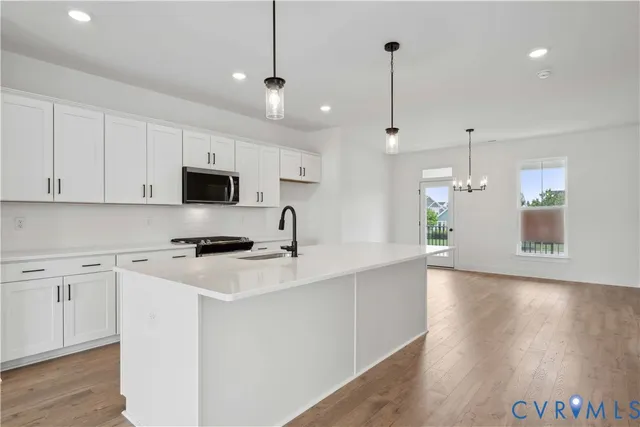 a kitchen with stainless steel appliances kitchen island a white cabinets and wooden floor