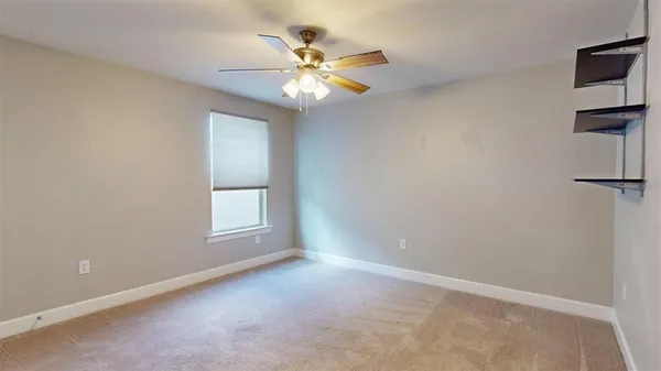 an empty room with chandelier fan and windows