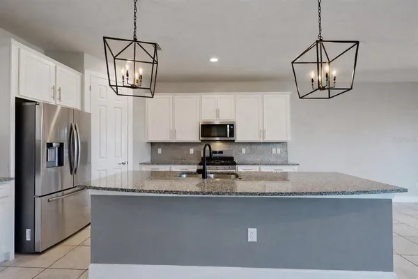 a kitchen with stainless steel appliances granite countertop a sink a microwave a refrigerator and white cabinets
