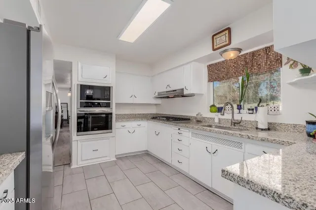 a kitchen with stainless steel appliances granite countertop a sink and white cabinets