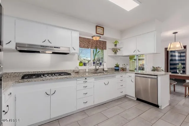 a kitchen with white cabinets and sink
