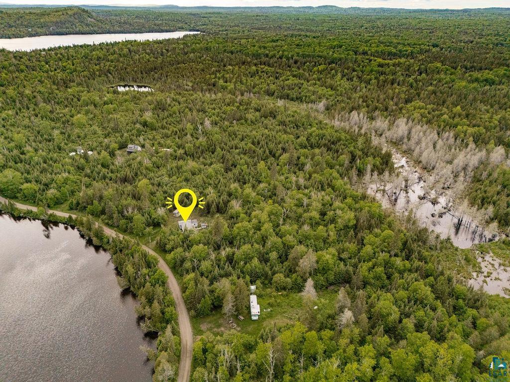 1268 Tom Lake Road Hovland, MN 55606 - Photo 53 of 56 Expansive wooded acreage featuring a single-story residence, a gravel access road, and direct waterfront access to a sizable body of water