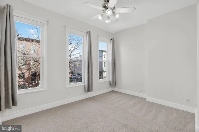 an empty room with windows and fan