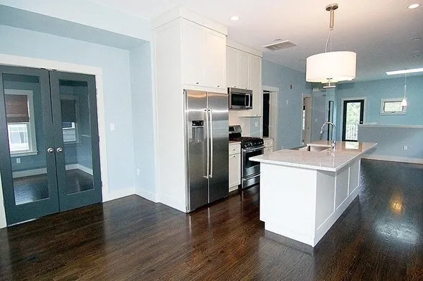 a kitchen with a refrigerator a sink and wooden floor