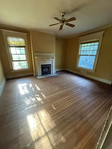 an empty room with windows and fireplace