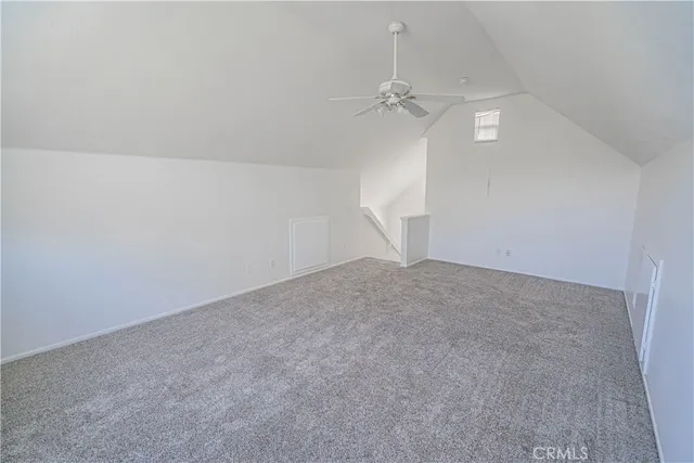 an empty room with a chandelier fan and wooden floor
