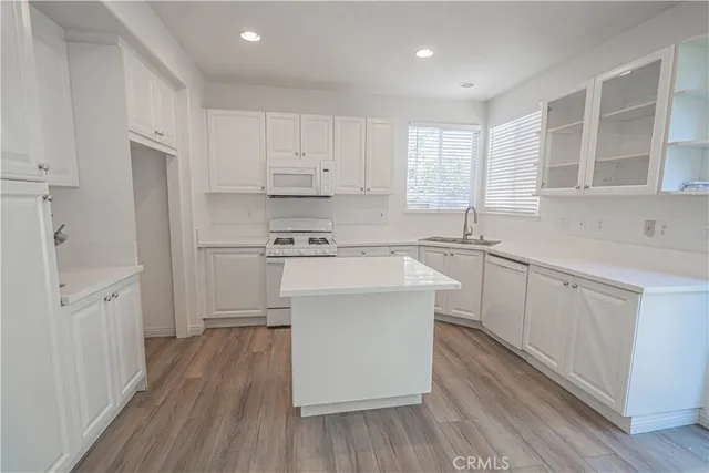 a kitchen with a sink wooden floor and stainless steel appliances
