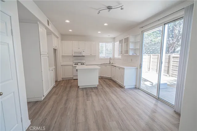 a kitchen with white cabinets and wooden floor