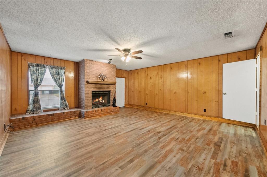 2305 Gilbert Circle Arlington, TX 76010 - Photo 11 of 38 an empty room with wooden floor fireplace and windows