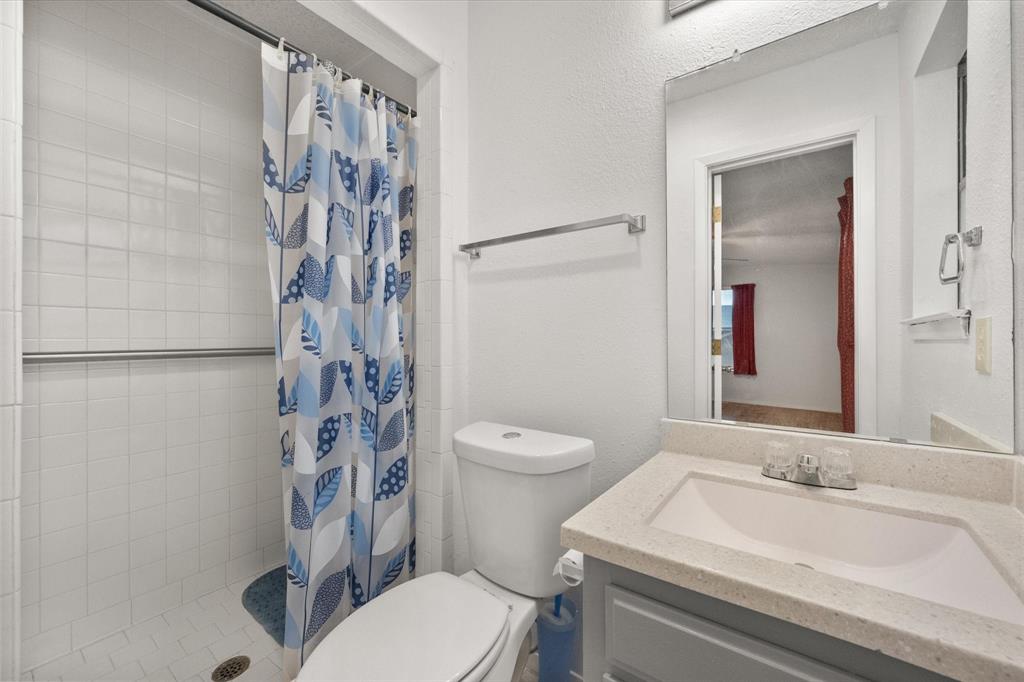 2305 Gilbert Circle Arlington, TX 76010 - Photo 22 of 38 a bathroom with a granite countertop toilet a sink and a mirror