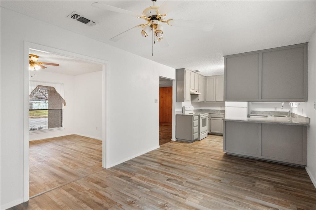 2305 Gilbert Circle Arlington, TX 76010 - Photo 27 of 38 a kitchen with stainless steel appliances granite countertop a refrigerator a sink dishwasher a stove and white cabinets with wooden floor