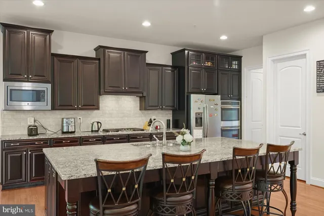 a kitchen with stainless steel appliances granite countertop a sink a stove a dining table and chairs