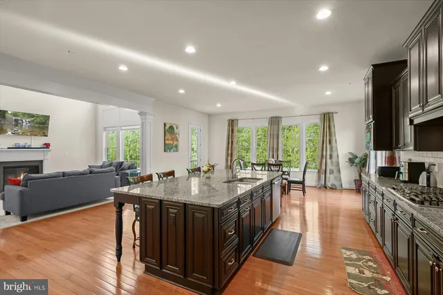 a large kitchen with stainless steel appliances a stove a sink dishwasher and a dining table with the living room view