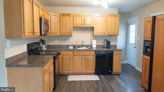 a kitchen with granite countertop wooden floors stainless steel appliances a sink and a window