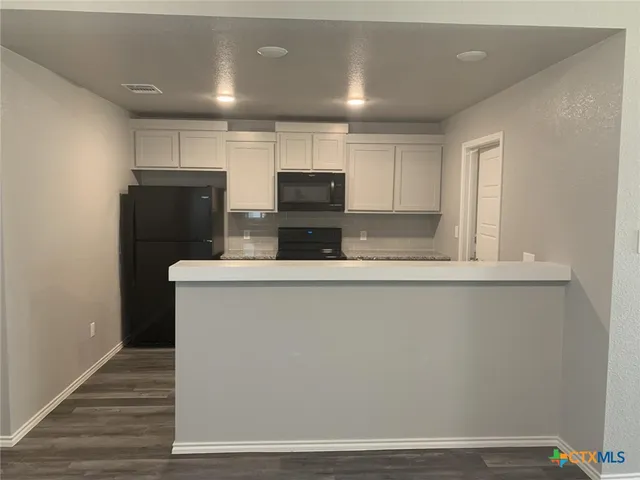 a kitchen with kitchen island a counter top space a sink and cabinets