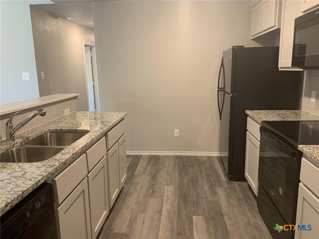 716 Kimble Drive, Unit B Temple, TX 76501 - Photo 5 of 23 a kitchen with granite countertop a refrigerator and a sink