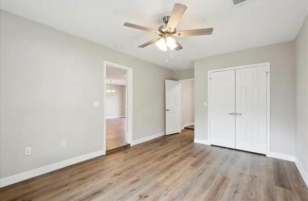 an empty room with wooden floor and ceiling fan