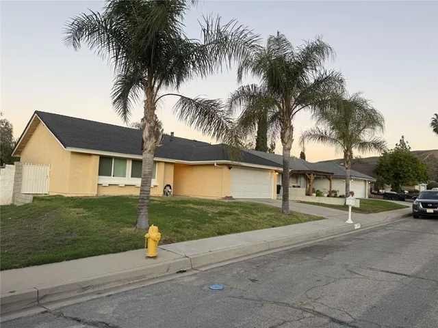 a view of a house with a yard and palm trees
