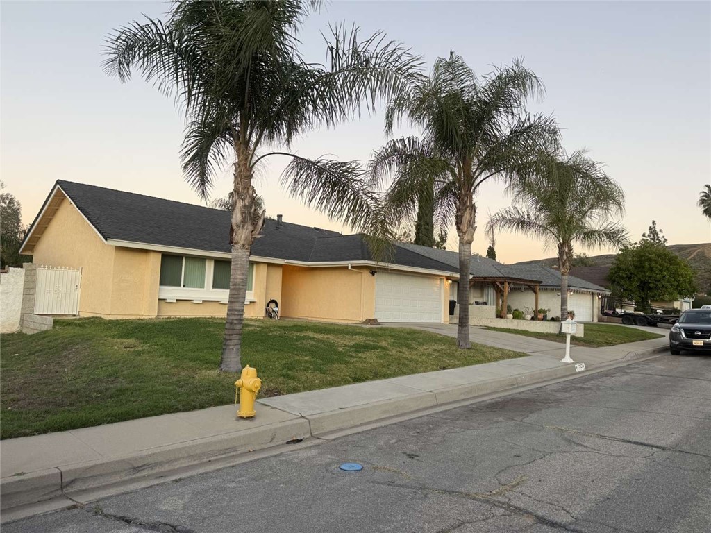 a view of a house with a yard and palm trees