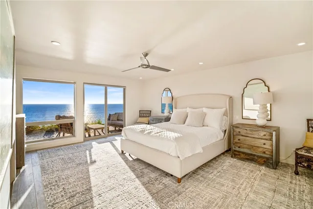 a spacious bedroom with a bed a table and large mirror with window