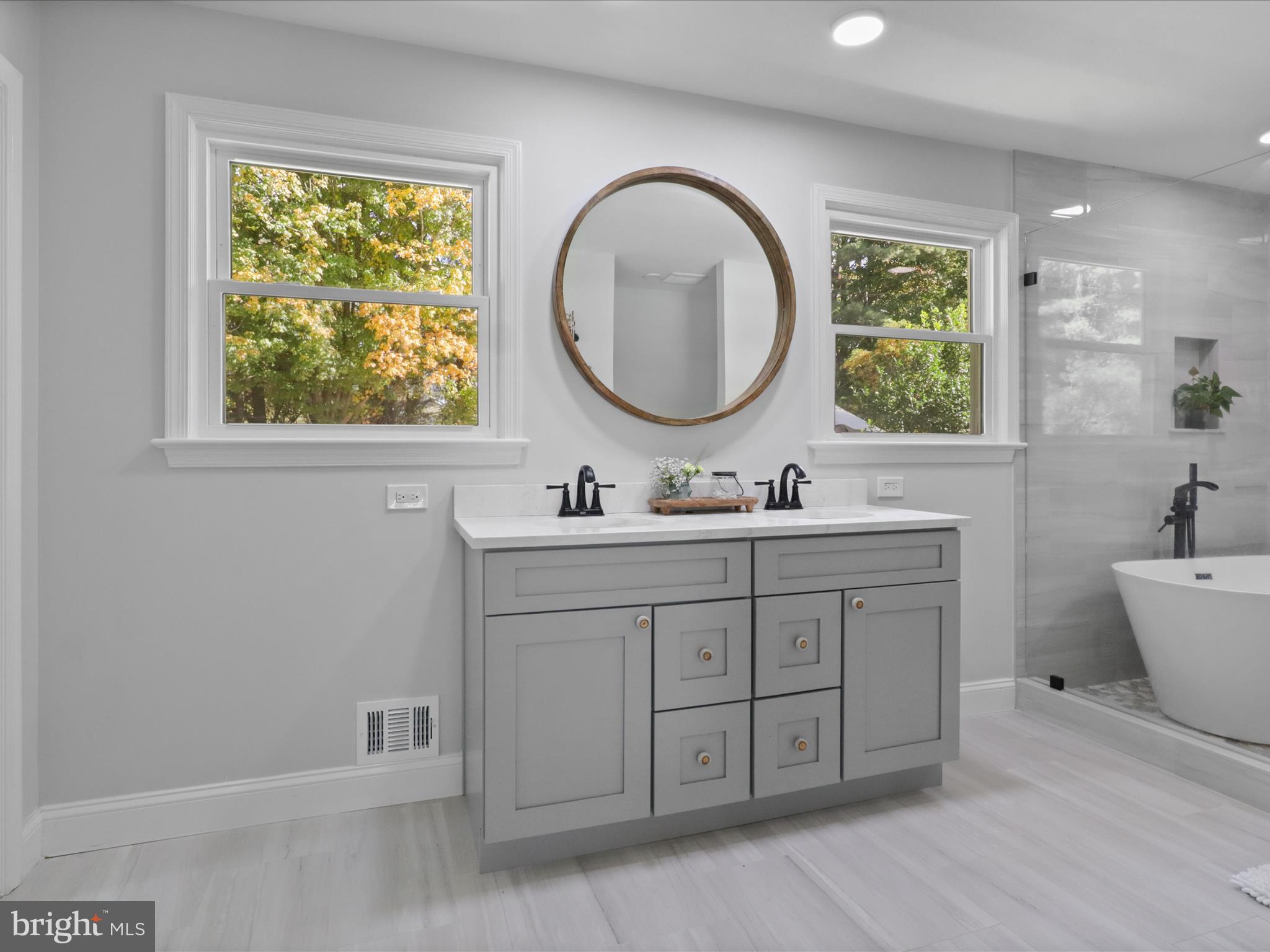 6811 White Rock Road Clifton, VA 20124 - Photo 48 of 87 a bathroom with a double vanity sink a two mirror a window and a bathtub