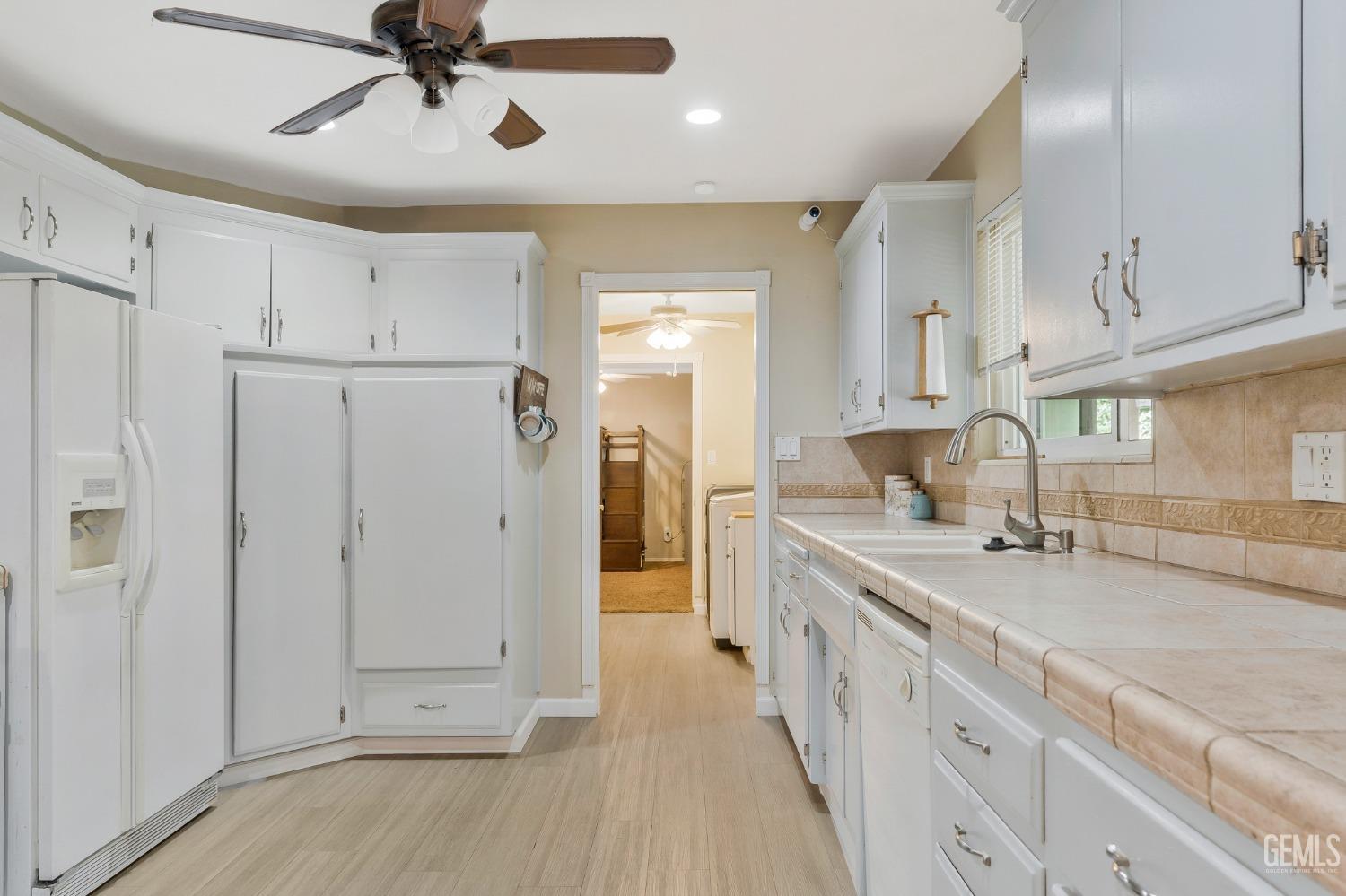 Undisclosed Address Bakersfield, CA 93306 - Photo 17 of 40 a large white kitchen with a lot of counter space and wooden floor