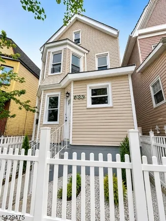 a front view of a house with white fence