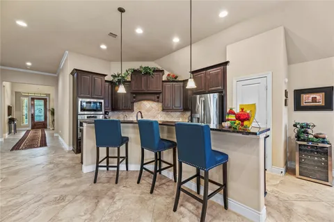 a kitchen with stainless steel appliances kitchen island granite countertop a dining table chairs refrigerator and sink