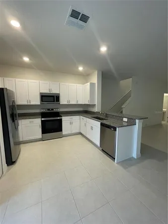 a large kitchen with stainless steel appliances kitchen island granite countertop a stove a sink a refrigerator a microwave and cabinets