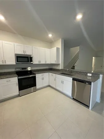a kitchen with stainless steel appliances granite countertop a stove a sink and a microwave