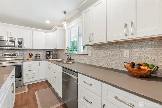 a kitchen with stainless steel appliances granite countertop a sink a stove and white cabinets