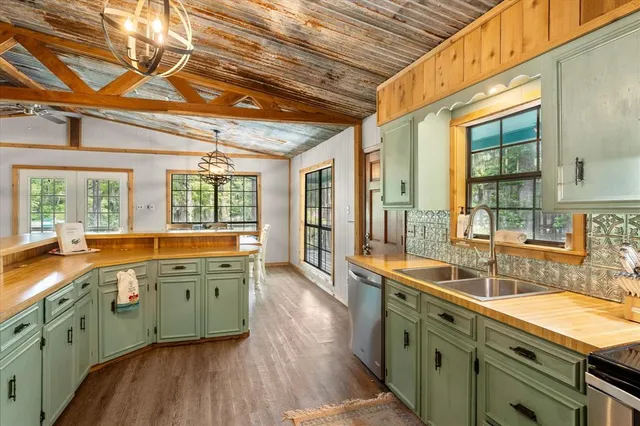 a large kitchen with stainless steel appliances granite countertop a sink and wooden cabinets