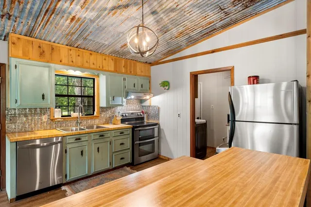 a kitchen with stainless steel appliances a refrigerator a sink a stove and cabinets