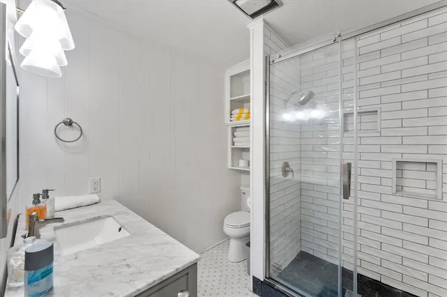 a bathroom with a granite countertop sink a toilet and shower