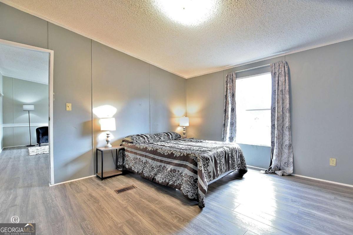 760 Hamilton Mulberry Grove Road Cataula, GA 31804 - Photo 13 of 26 a spacious bedroom with a bed and wooden floor