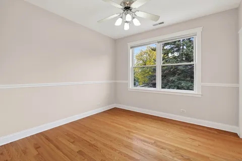 an empty room with wooden floor cabinet and windows