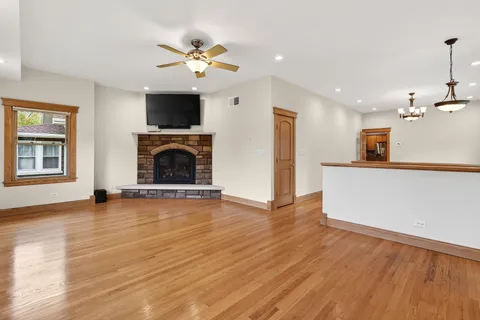 a view of a livingroom with a fireplace a ceiling fan and windows