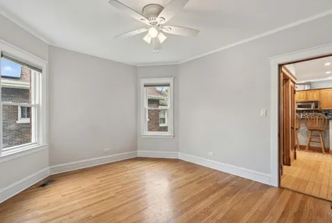 an empty room with wooden floor chandelier fan and windows
