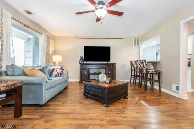 a living room with furniture a dining table and a potted plant with wooden floor